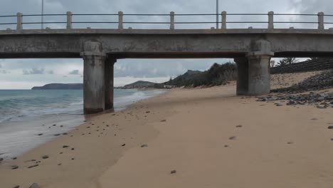 first-person shot along sandy beach and under pylon of pier