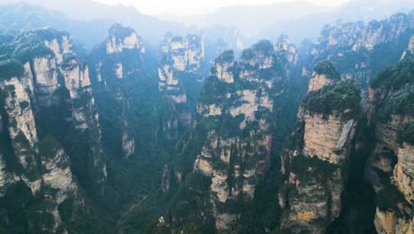 aerial shot showing the pillars within zhangjiajie national park with misty look