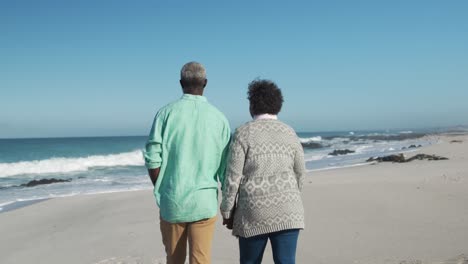 senior couple walking besides the beach