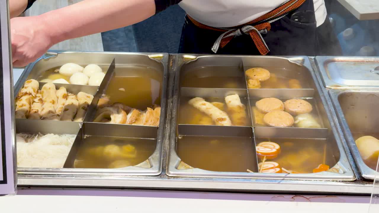 Primo piano di ingredienti oden fumanti che sobbollono in brodo presso una bancarella di street food a Kanazawa
