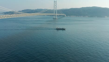 barco navegando más allá del puente akashi kaikyo con la isla awaji en la distancia