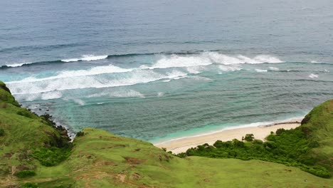 empty white sand tropical beach at bukit merese lombok with turquoise waves crashing, aerial