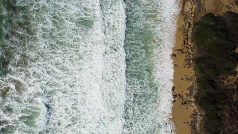 line between powerful ocean and sandy coastline, top down view