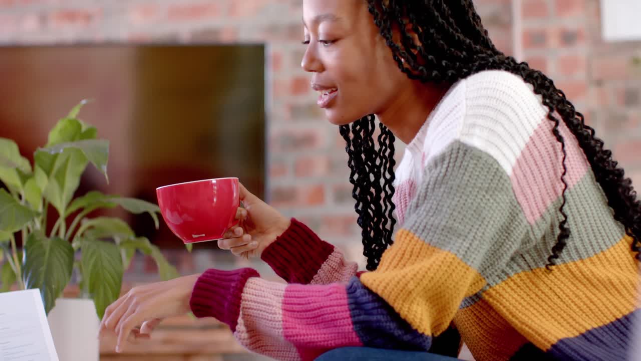 행복한 아프리카계 미국인 캐주얼 사업가 여성이 커피를 마시며 사무실에서 동료와 이야기하고 있습니다.