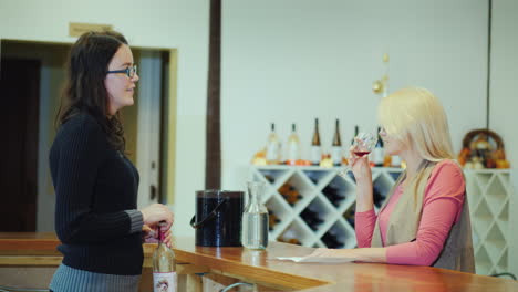 a woman tastes wine in a small winery communicates with the seller