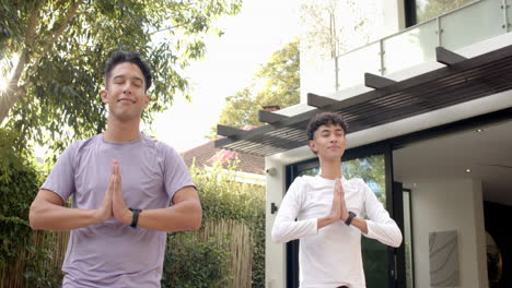 practicing yoga, multiracial gay couple meditating together outdoors in peaceful setting