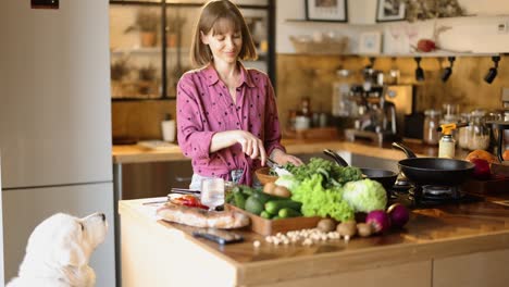 woman cooking healthy food and feeding her dog in the kitchen