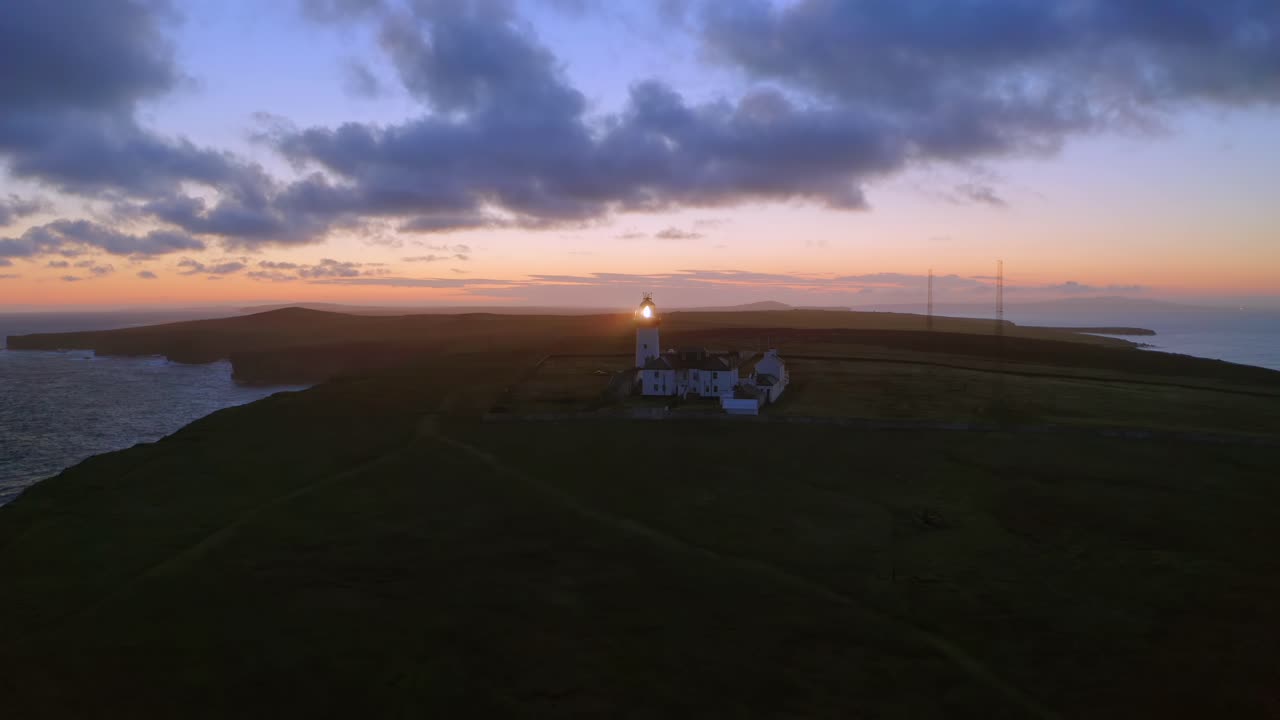 Aerial pullback and ascent of lighthouse beaming in beautiful morning light