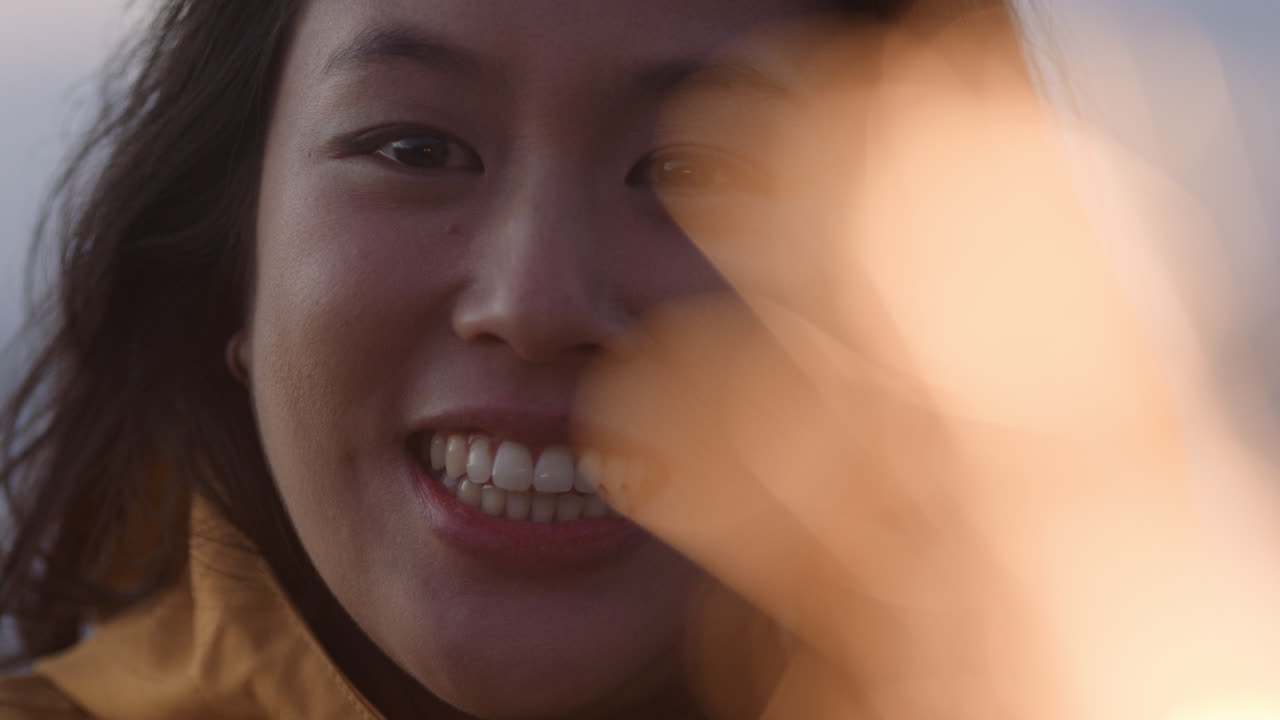 retrato de cerca de una mujer asiática feliz sosteniendo bengalas celebrando la víspera de año nuevo sonriendo disfrutando de la celebración del día de la independencia en la playa al atardecer
