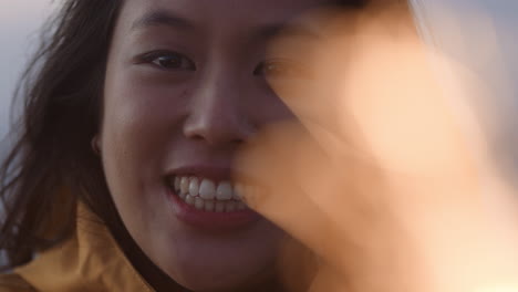 close up portrait of happy asian woman holding sparklers celebrating new years eve smiling enjoying independence day celebration on beach at sunset