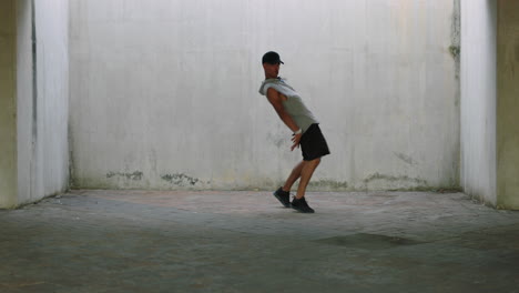 bailarín joven bailarín de calle talentoso breakdancing realizando varios movimientos de baile de estilo libre adecuado hombre de raza mixta practicando en un almacén grungy
