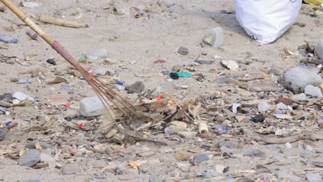 Mann-Sammelt-Plastikmüll-Mit-Rechen-Landwirtschaftswerkzeug-In-Carter-Road-Beach-Mumbai-Indien-Nahaufnahme