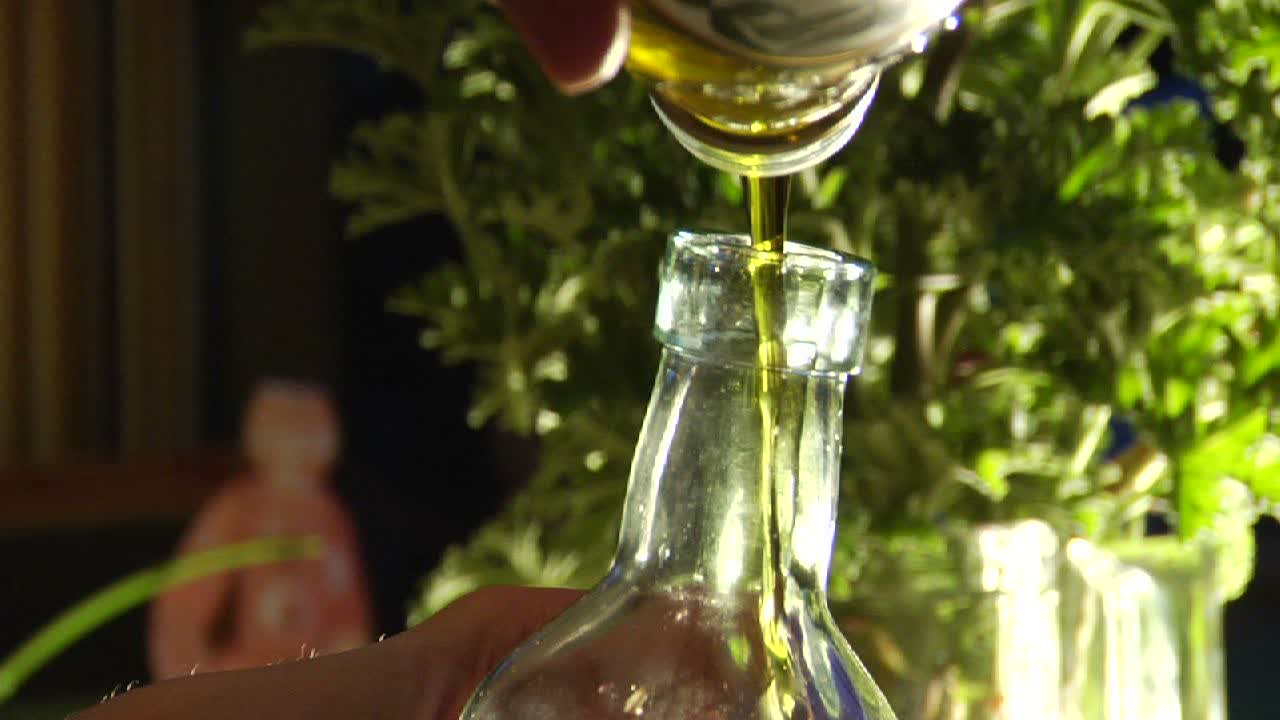 un hombre vierte aceite de oliva en una botella