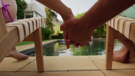Focus-on-happy-Caucasian-couple-holding-their-hand-near-the-pool-