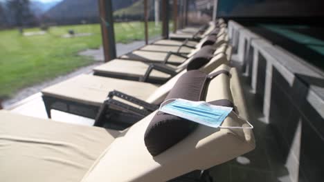 Face-mask-on-a-deckchair-next-to-a-swimming-pool-in-a-hotel