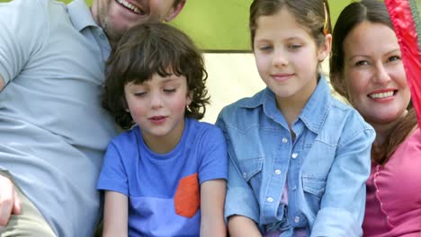 Happy-family-sitting-in-their-tent-on-a-camping-trip