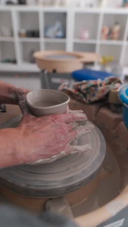 hands shaping clay on a pottery wheel