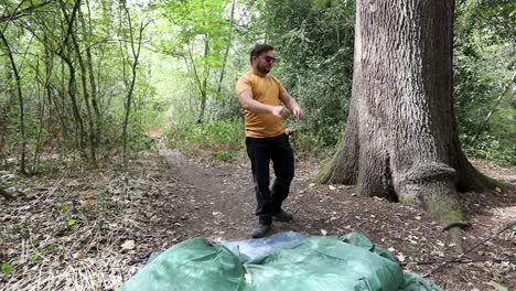 angry man who fails to assemble a camping tent and throws it on the ground at a campsite in the forest
