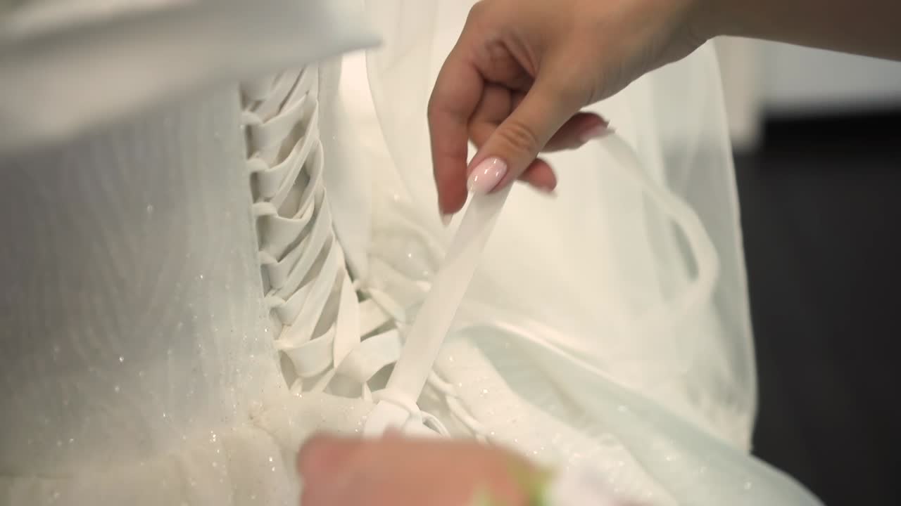 подружка невесты помогает невесте застегнуть корсет крупным планом