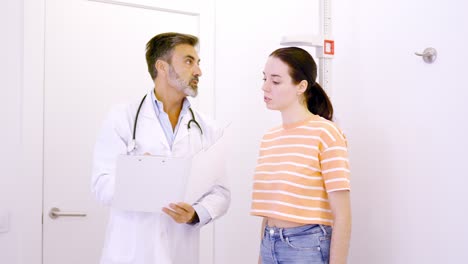 doctor taking notes in a report while assisting a patient