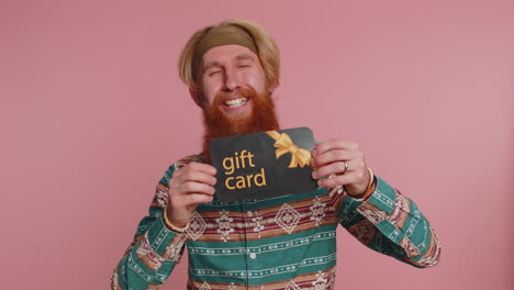 young hippie man showing pointing gift discount certificate voucher coupon for store holidays sale