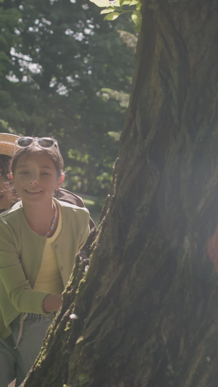 People hiding behind a tree in a park