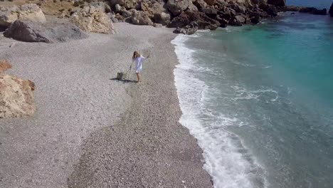 Toma-Aérea-Sobre-Una-Mujer-Cantando-En-La-Playa-Con-Un-Vestido-Blanco-Y-Un-Micrófono-Vintage