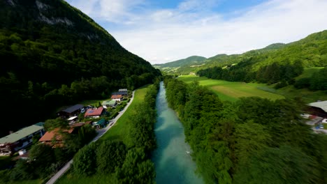 drone fpv volando sobre un río con agua turquesa y una carretera rodeada de montañas verdes de austria
