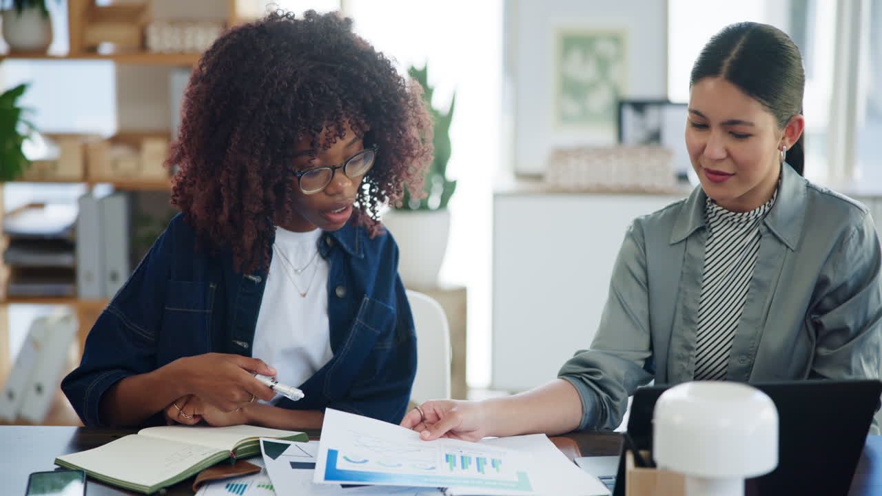 Two Diverse Businesswomen Collaborating and Discussing Documents in Office