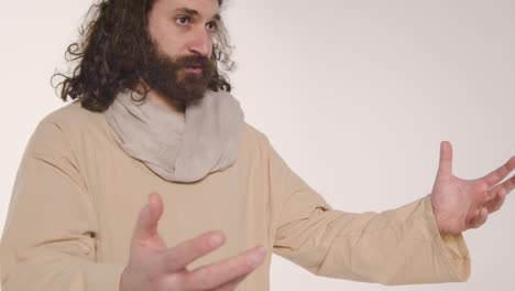 portrait of man wearing robes with long hair and beard representing figure of jesus christ raising hands and preaching