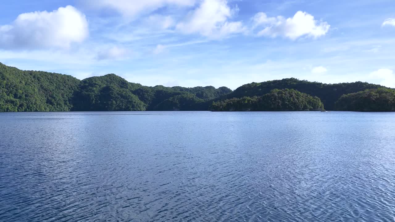 動くボートからの広角ショットが、緑豊かなカルストの島々とターコイズブルーの水を捉える