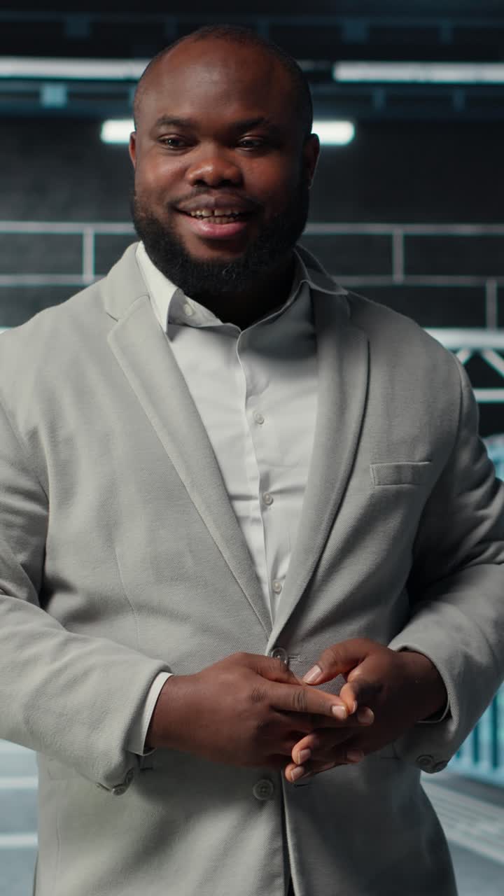 Vertical video Smiling engineer walking in data center facility with rows of supercomputers