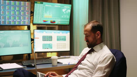 corredor de bolsa con traje y corbata escribiendo en la computadora portátil