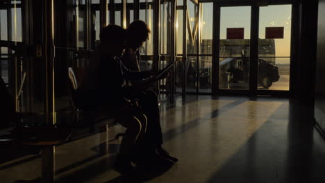 at airport of thessaloniki greece in the waiting room sits a mother with her son and watching videos on tablet