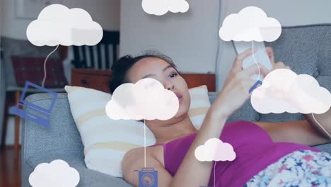 Animation-of-clouds-and-media-icons-over-woman-using-smartphone