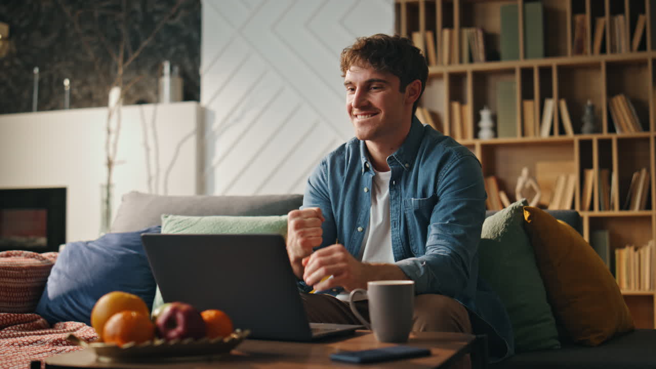 hombre de negocios regocijándose mirando pantalla de portátil sofá de casa. trabajador independiente celebrando