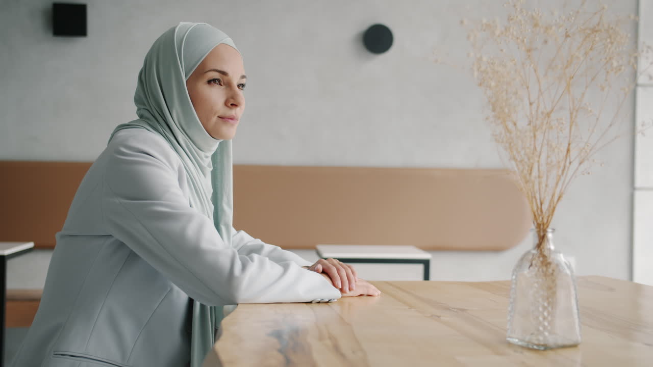 Woman in Hijab Sitting at a Cafe Table