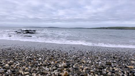 pebbles and sand with gentle waves, calm of an irish beach