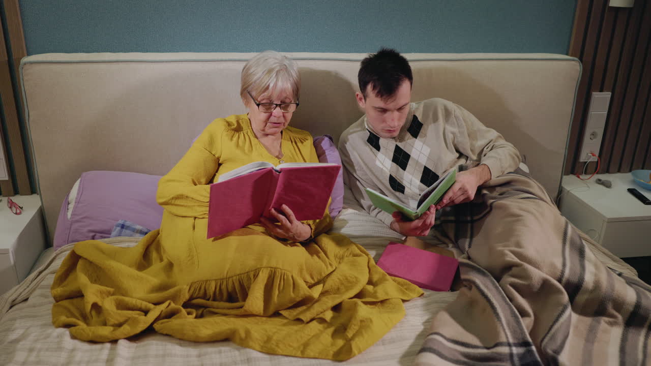 할아버지, 할머니와 손자가 침대에서 책을 읽고 있다.