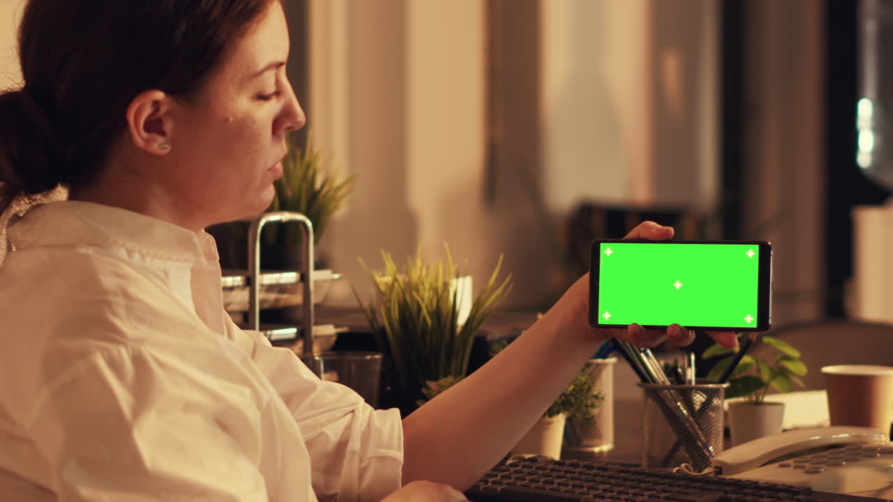 Female manager holding smartphone with greenscreen display