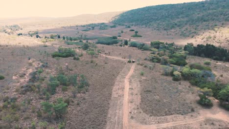 safari jeep on dirt road in african savannah landscape, drone shot