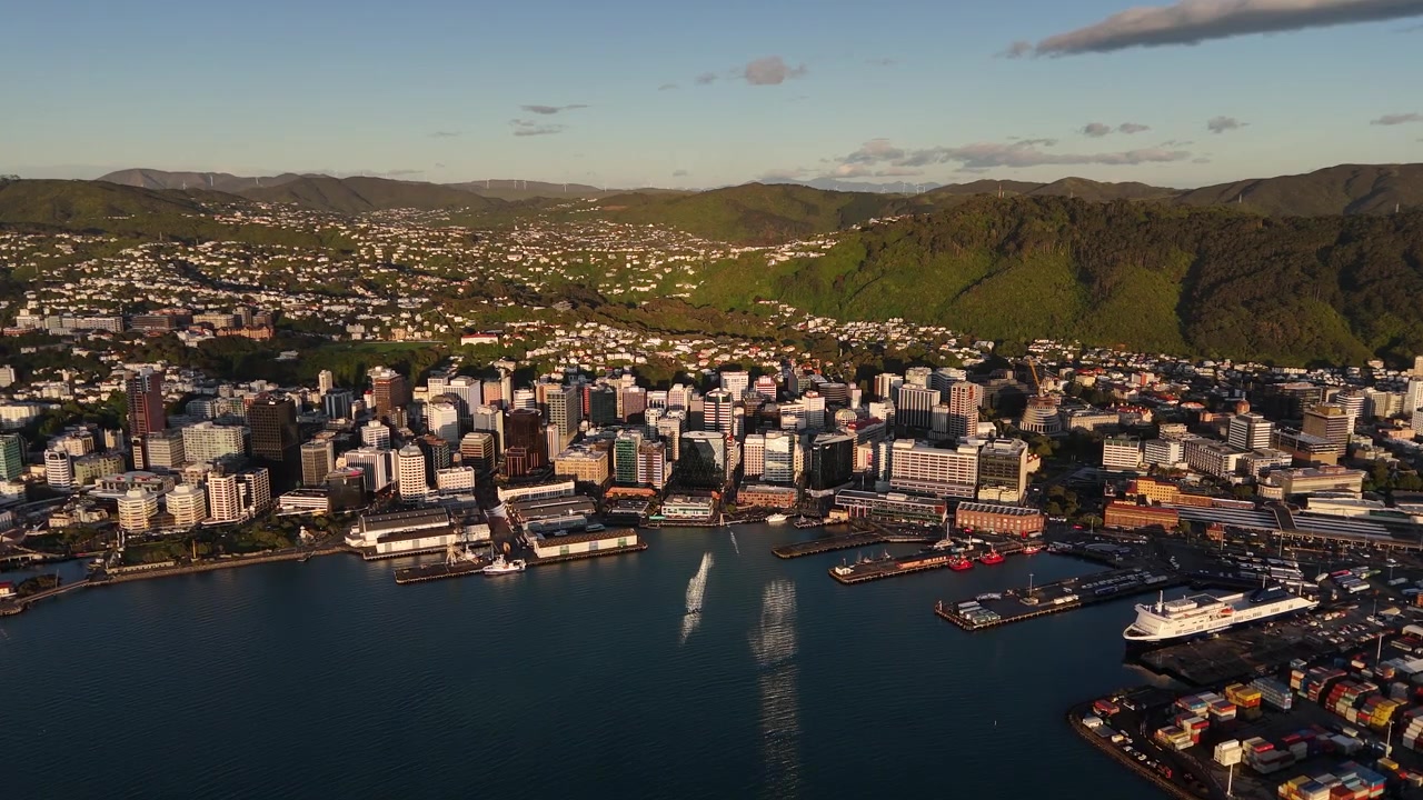 Edifici moderni e porto illuminati dalla luce del primo mattino con colline sullo sfondo a Wellington, Nuova Zelanda. Vista panoramica aerea con drone.