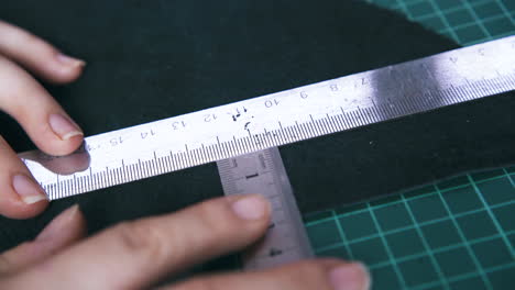 tailor moves metal rulers measuring black leather cloth