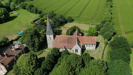 aerial upward tilt shot of st john the evangelist church in ickham, kent, with a few village houses in the background