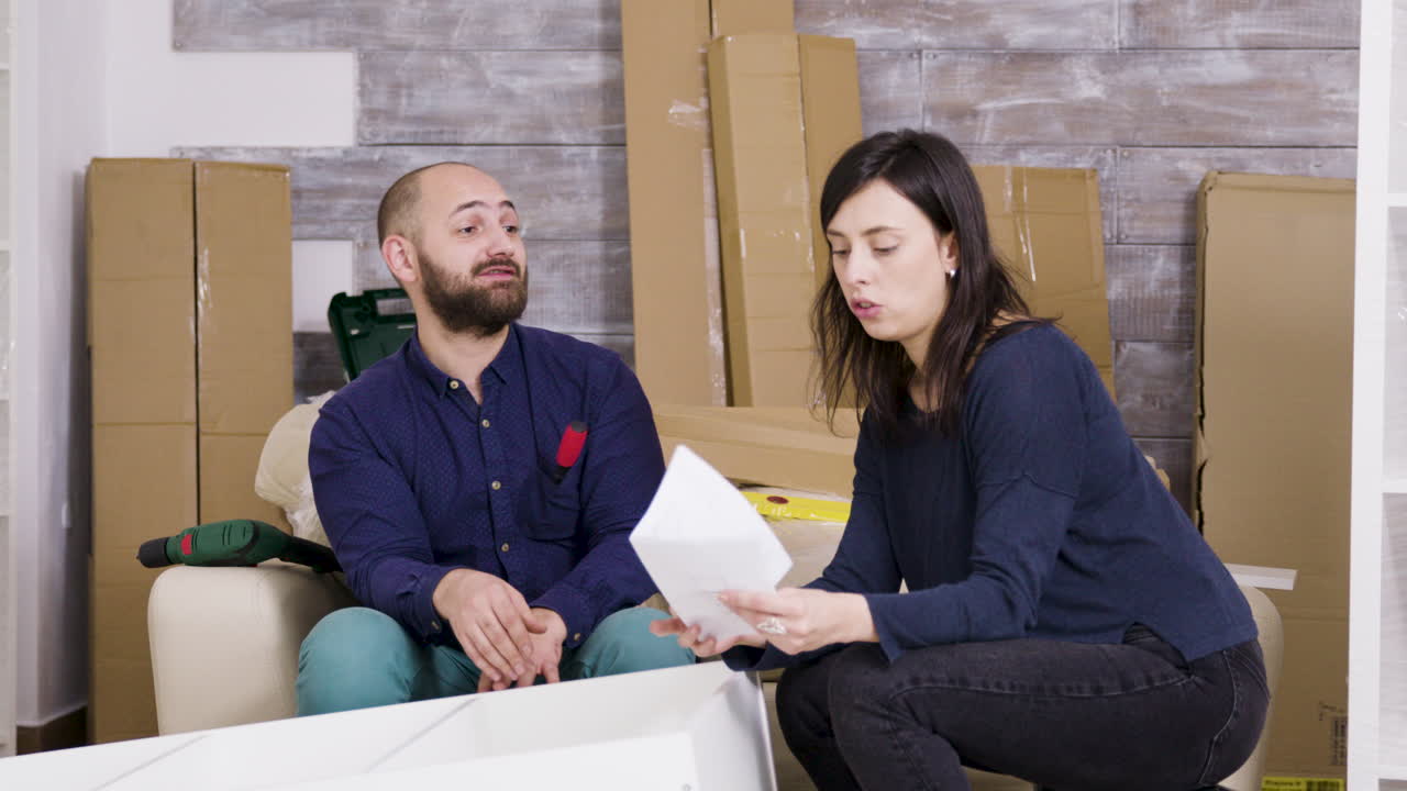 Couple assembling furniture in new apartment