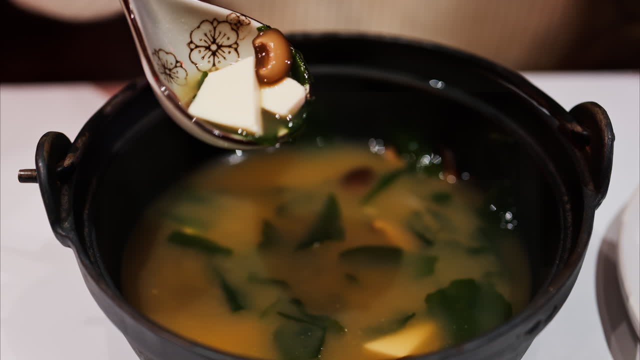 Close up of a woman mixing a miso soup at a restaurant