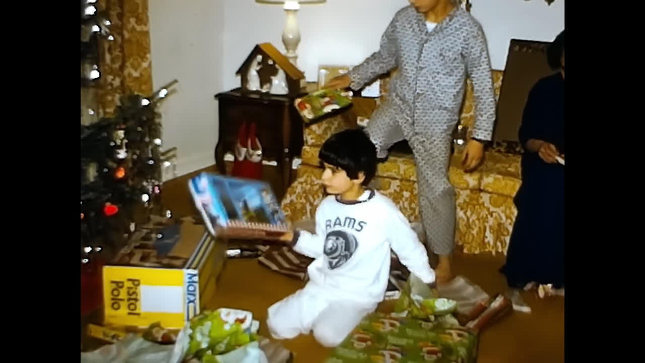 Little Boy Playing With a Christmas Tree. CIRCA USA - 1970s: A young boy in the 1970s USA is seen joyfully playing with a Christmas tree, surrounded by holiday decorations.