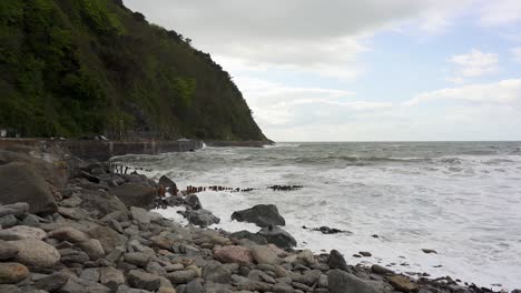 frothy waves crash agianst the rocky beach and sea defences in lynmouth on a very windy day