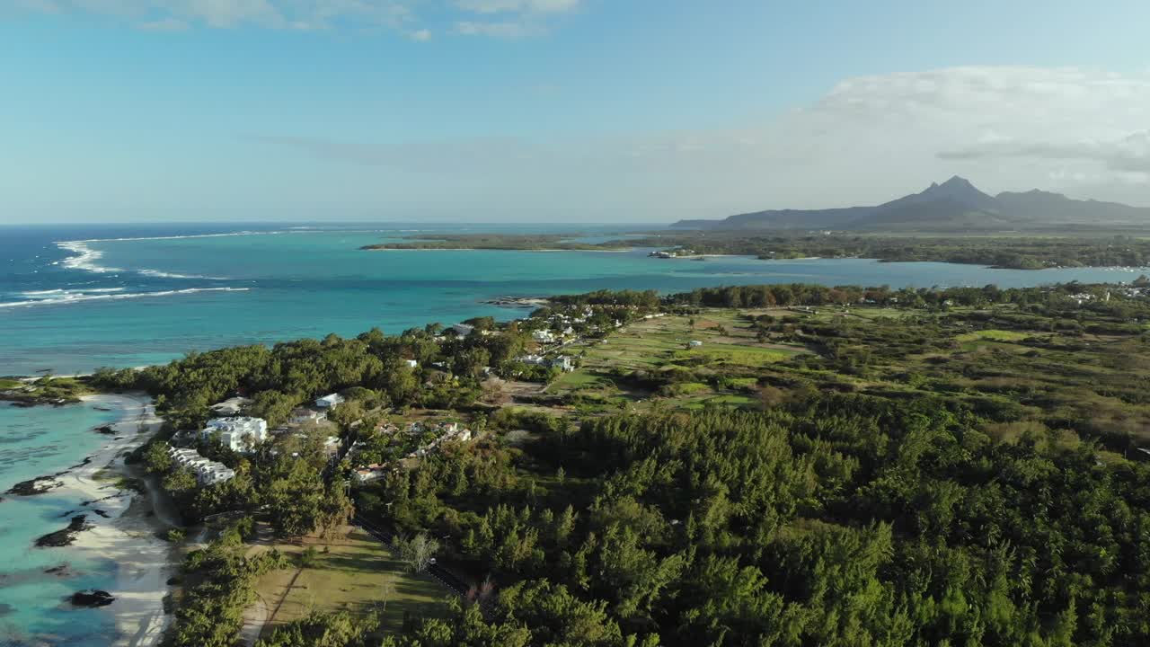 산을 배경으로 해변을 때리는 파도의 드론 샷