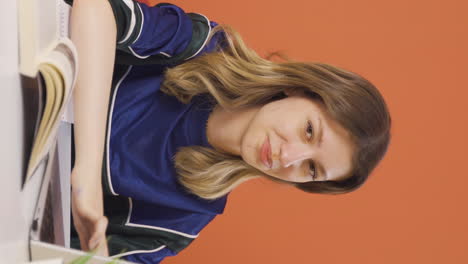 video vertical de una mujer joven mirando una computadora portátil haciendo un gesto positivo.